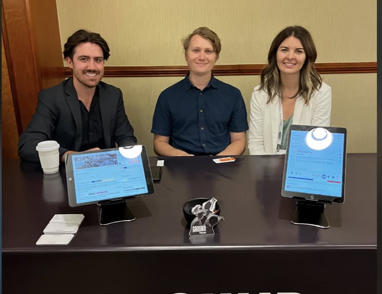 Three Ground News team members sitting at a table with laptops